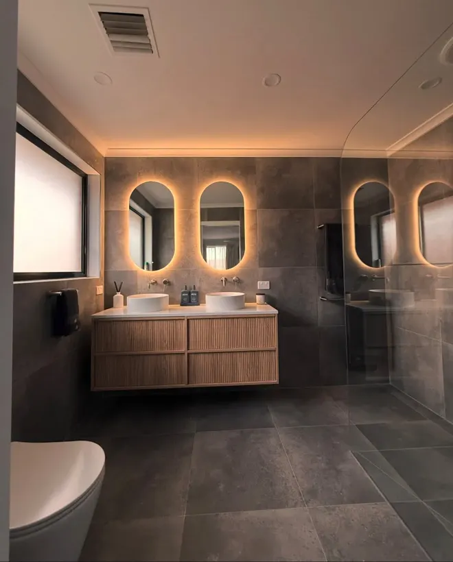 Bathroom renovation by MFM Plumbing in Melbourne with backlit oval mirrors, double vessel basins and wall-mounted mixers